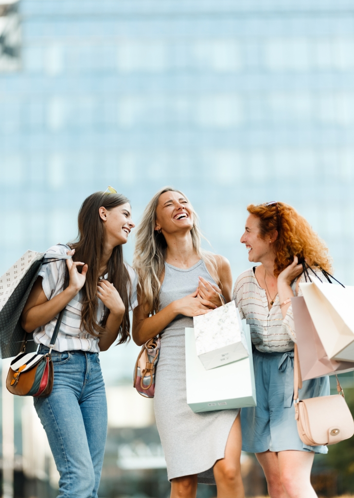 a group of women laughing while holding shopping bags