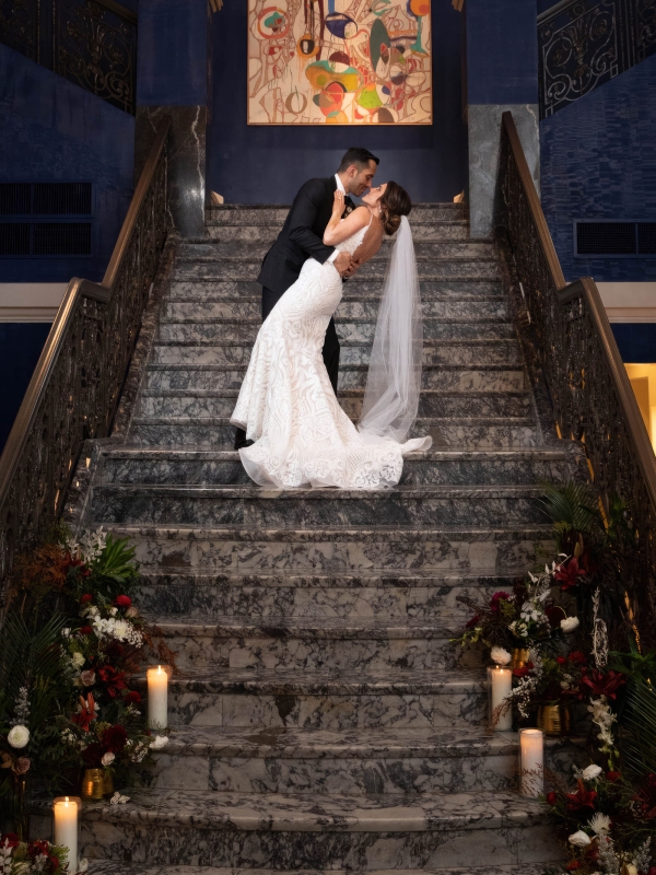 A bride and groom preparing for a kiss while standing on the stairs at The Marker