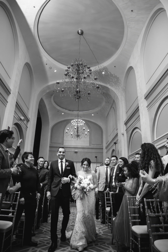A bride and groom walking down the isle at The Marker in black and white