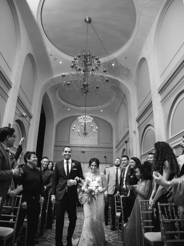 Black and white image of a bridge and groom walking down the isle at The Marker