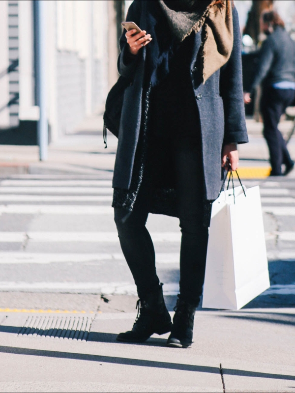 A woman standing on the sidewalk using her phone