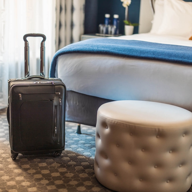 Luggage sitting next to a chair in front of a bed at The Marker