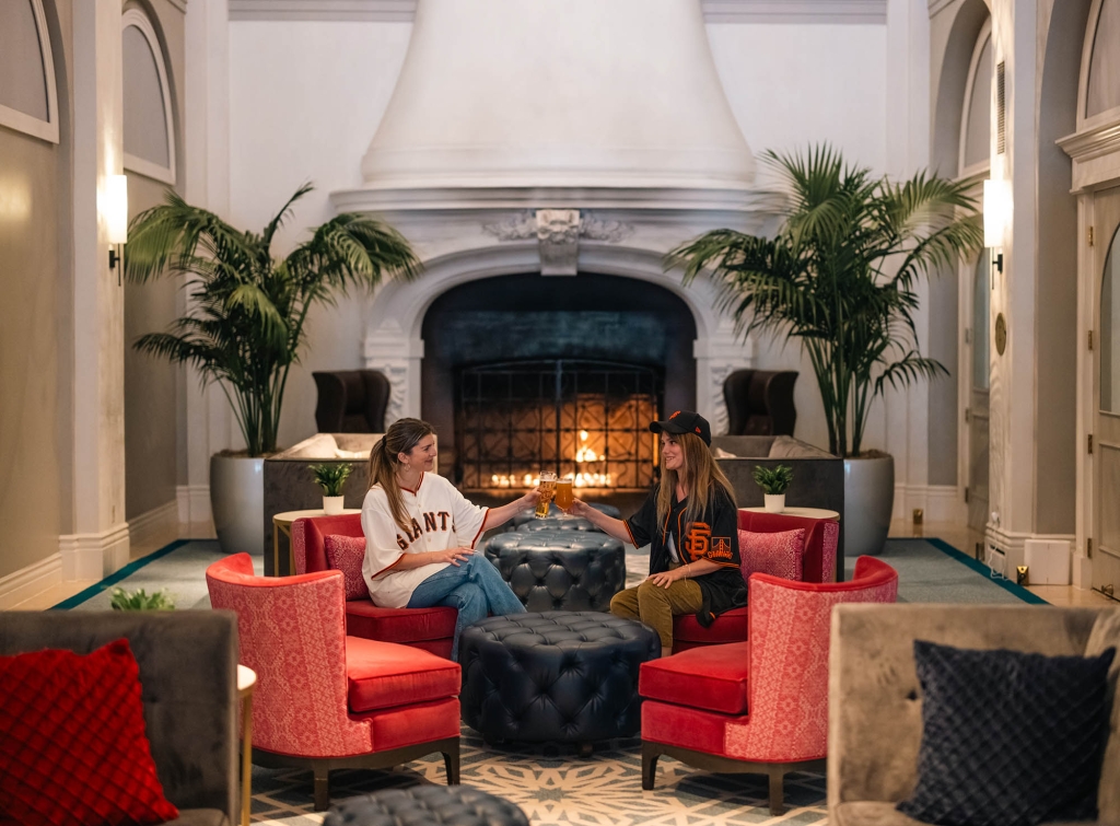 Two women having drinks while dressed up in San francisco sports apparel